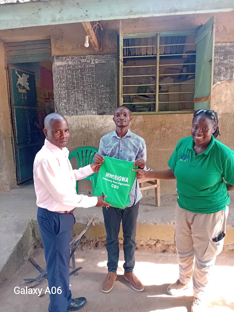 A Mwesigwa CBO representative presenting a branded learner-support bag